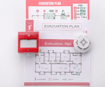 Evacuation plans, smoke detector and manual call point on white background