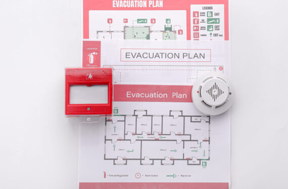 Evacuation plans, smoke detector and manual call point on white background