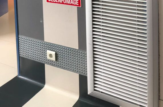 illustration d'une trappe de désenfumage de couleur grise sur un mur avec sa pancarte à coté de couleur rouge et blanche